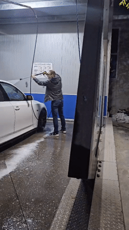 Man power-washes white sedan at Kazanlak car wash facility