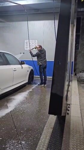 Man power-washes white sedan at Kazanlak car wash facility