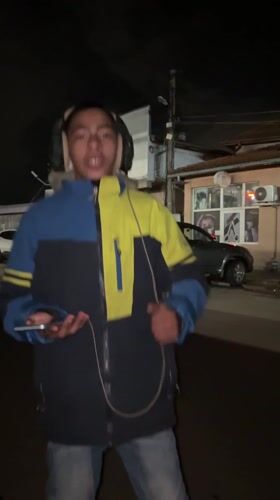 Young man dances with headphones outside Bulgarian cafe at night