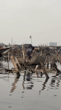 Person poles makeshift concrete boat through Lagos waterway