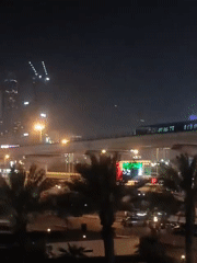 Metro train crosses illuminated bridge in Dubai cityscape
