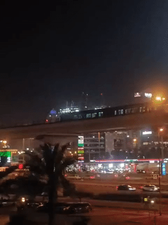 Metro train crosses illuminated bridge in Dubai cityscape