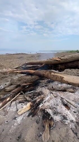 Burning log pile on a sandy beach in Krasnoturansk