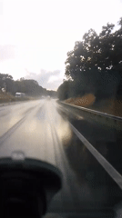 Driving through rain on a reflective highway at dusk