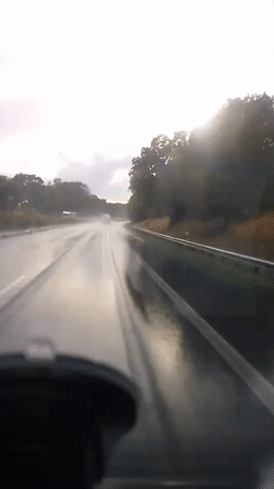 Driving through rain on a reflective highway at dusk