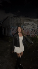 Woman poses for photos near graffitied building in Kuta