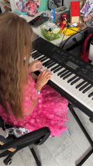 Girl plays keyboard while being recorded in Belarus home