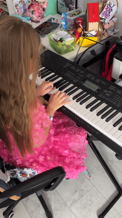 Girl plays keyboard while being recorded in Belarus home