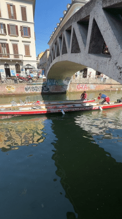 Boats navigate Milan canal on sunny morning