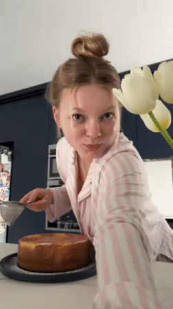Woman decorates homemade cake in pajamas Saturday afternoon