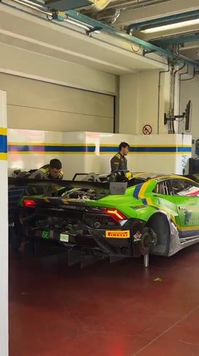 Lamborghini race cars prepped in Scarperia paddock alongside a roaming robot dog