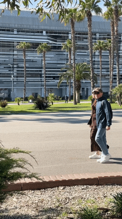 Two people walk through sunny park in Sirius, Russia
