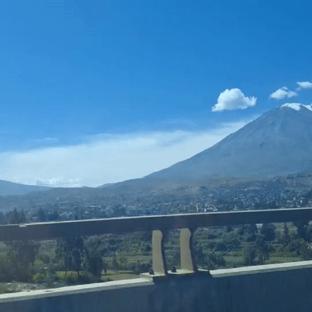Vehicle crosses bridge overlooking Arequipa beneath snow-capped mountain