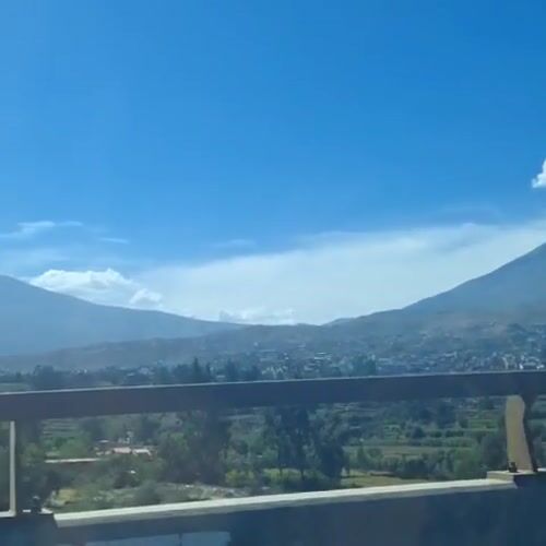Vehicle crosses bridge overlooking Arequipa beneath snow-capped mountain
