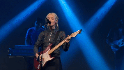 Blonde guitarist performs on Milan stage under blue lights