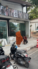 Buddhist monk walks street carrying yellow object in Thailand