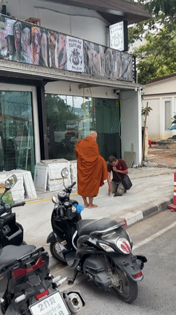 Buddhist monk walks street carrying yellow object in Thailand