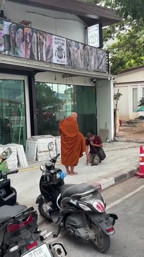 Buddhist monk walks street carrying yellow object in Thailand