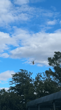 Red helicopter hovers over Plovdiv during afternoon car wash