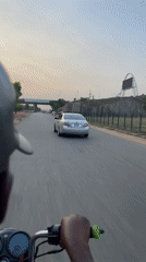 Motorcycle rider travels through Kuchingoro, Nigeria at evening