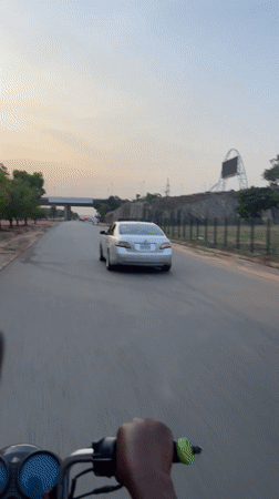 Motorcycle rider travels through Kuchingoro, Nigeria at evening