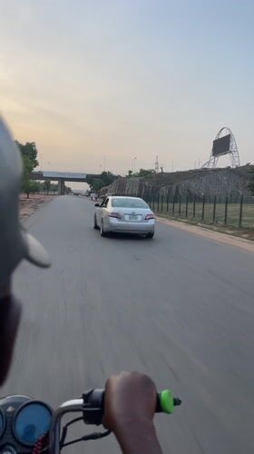 Motorcycle rider travels through Kuchingoro, Nigeria at evening