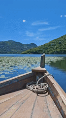 Wooden boat sails peacefully on Montenegro lake amid sunny weather