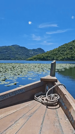 Wooden boat sails peacefully on Montenegro lake amid sunny weather