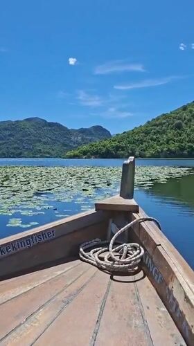 Wooden boat sails peacefully on Montenegro lake amid sunny weather