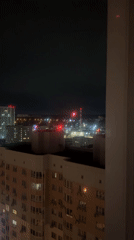 Moscow nighttime cityscape observed through window, industrial smokestack visible