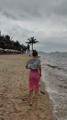 Woman runs barefoot on overcast beach in Vietnam