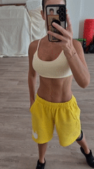 Woman takes gym mirror selfies in yellow athletic wear