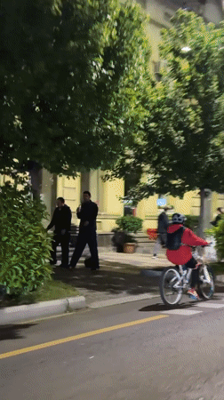Cyclist in red jacket rides white bike through Tbilisi