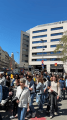 Diverse crowd crosses Barcelona street on sunny Saturday morning