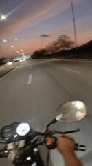 Motorcycle rider travels empty road at dusk in Altagracia