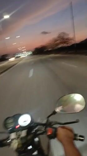 Motorcycle rider travels empty road at dusk in Altagracia
