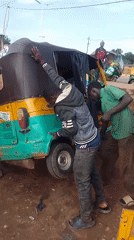 Two men help lift overturned rickshaw in Bukuru