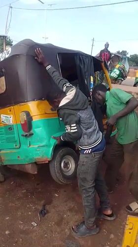 Two men help lift overturned rickshaw in Bukuru