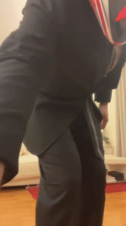 Person in suit and motorcycle gear poses, dances indoors