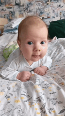 Baby enjoys tummy time on bed in Andreyevo
