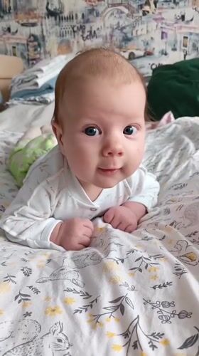Baby enjoys tummy time on bed in Andreyevo