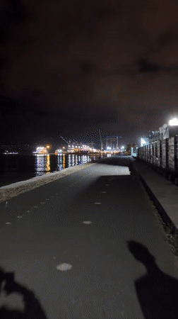 Nighttime harbor walkway documented in Lisbon with industrial lighting