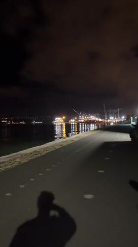 Nighttime harbor walkway documented in Lisbon with industrial lighting