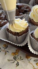 Baker decorates chocolate brownie cupcakes with yellow rose frosting
