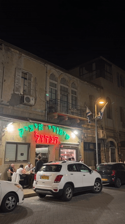 Evening diners gather at illuminated HaKtzav restaurant in Tel Aviv