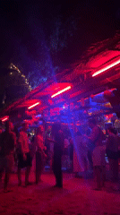 Night beach party illuminated by colorful lights in Thailand