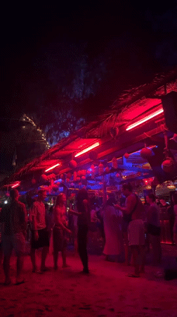 Night beach party illuminated by colorful lights in Thailand