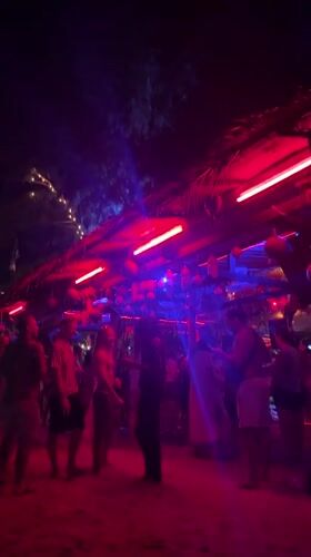 Night beach party illuminated by colorful lights in Thailand