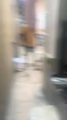 A man is standing outside. He turns off a faucet. He is standing next to a barbell, a white bucket, and a white washing machine. The man turns on the washing machine.