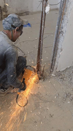 Construction worker cuts metal with grinder in Bat Yam